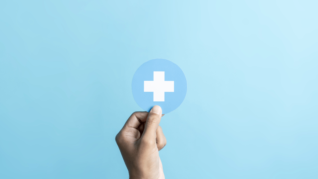 Person holding a white plus sign symbolizing health insurance clarity and simplified coverage terms.