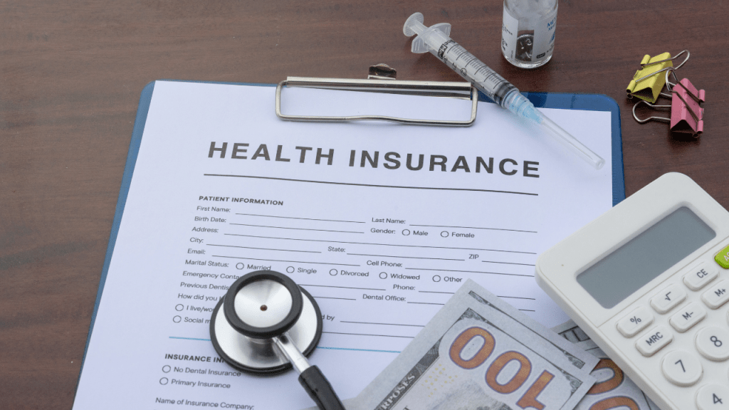 A calculator, hundred dollar bill, prescription medication, and health insurance application laid out together representing the financial stress and urgency of finding COBRA alternatives and health coverage after job loss