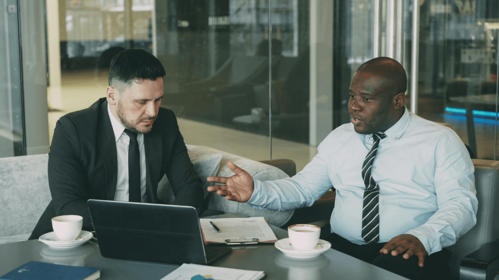Two businessmen meeting one on one as a health insurance advisor helps an individual without employer coverage explore cost saving strategies and COBRA alternatives